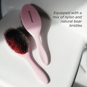Denman brush smoothing hair into a slick-back demonstrating frizz control and sleek styling
