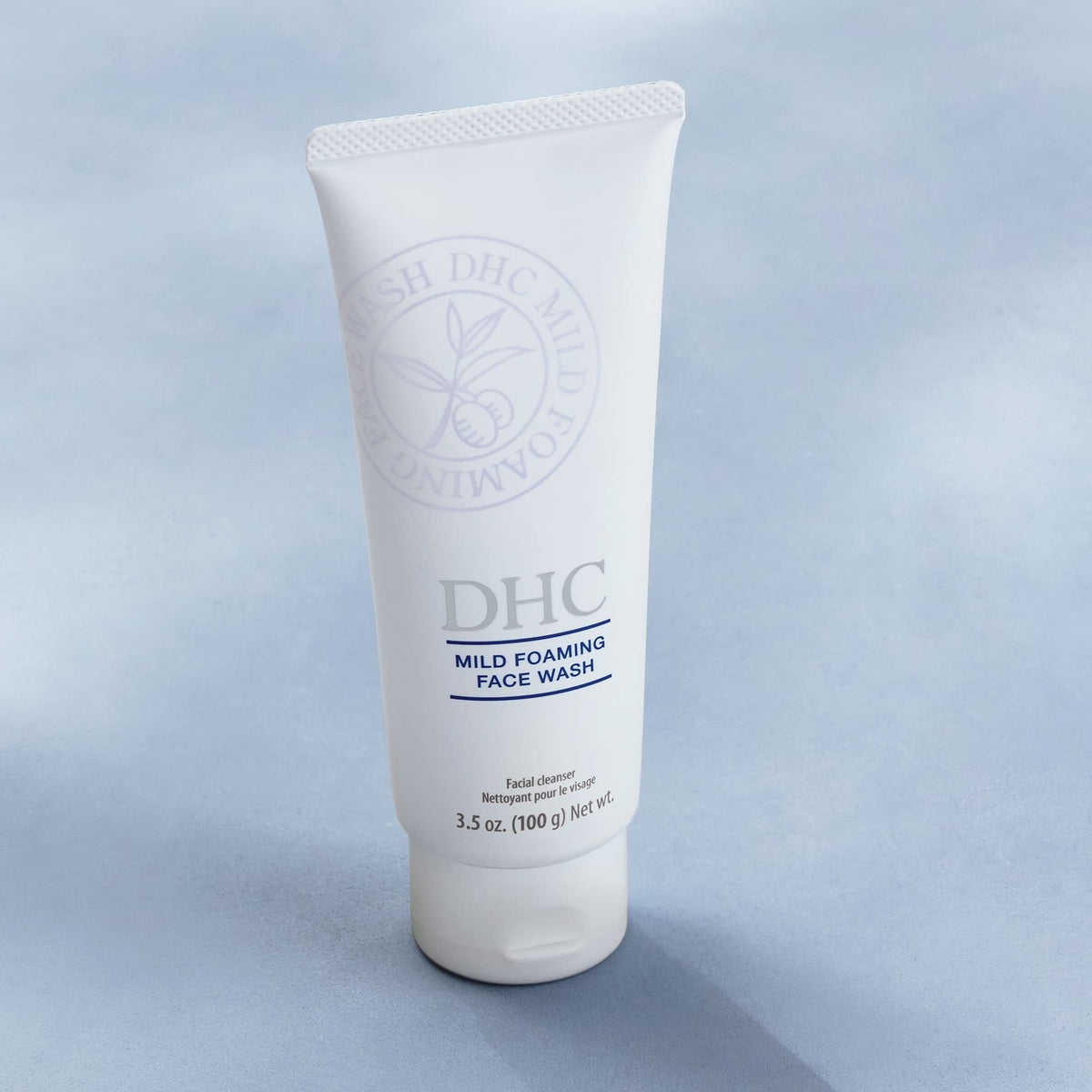 DHC tube held next to hand to show 3.5 oz travel-friendly scale