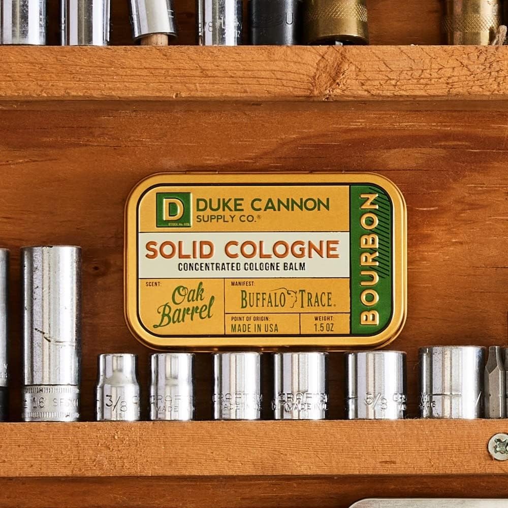 Duke Cannon bourbon solid cologne being applied with fingertips for precise scent