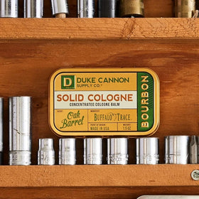 Duke Cannon bourbon solid cologne being applied with fingertips for precise scent