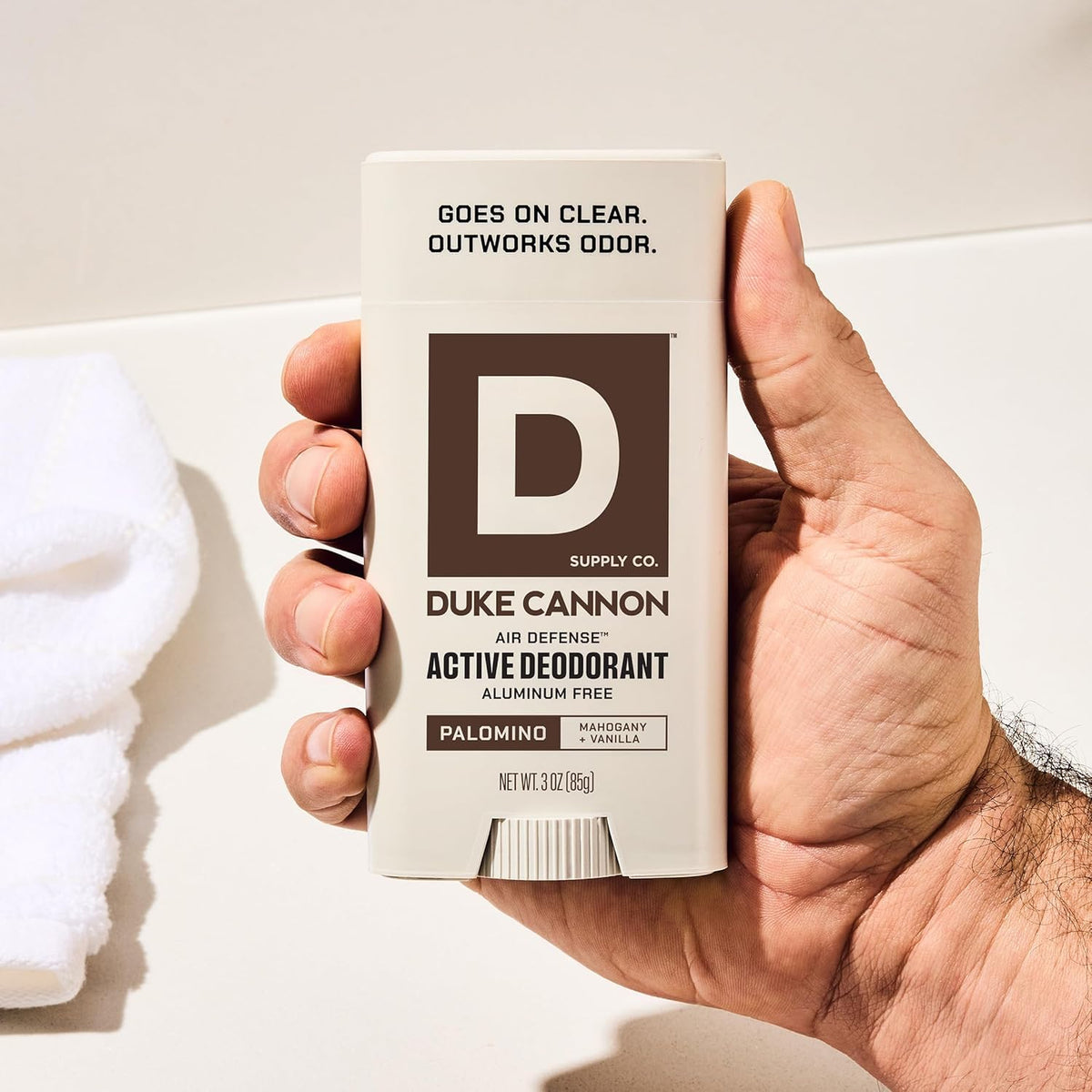 Duke Cannon Palomino next to phone showing compact 3 oz travel-friendly benefit