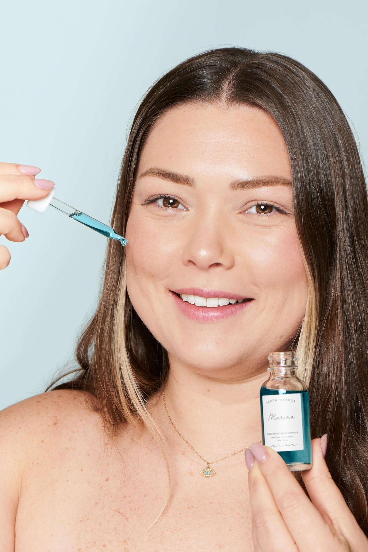 Hand with a few drops of MARINA ampoule to show absorption and how little product is needed