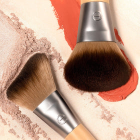 EcoTools brushes held in hand for scale showing compact, travel-friendly design