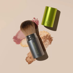 EcoTools brush next to a coin showing compact size and easy travel convenience
