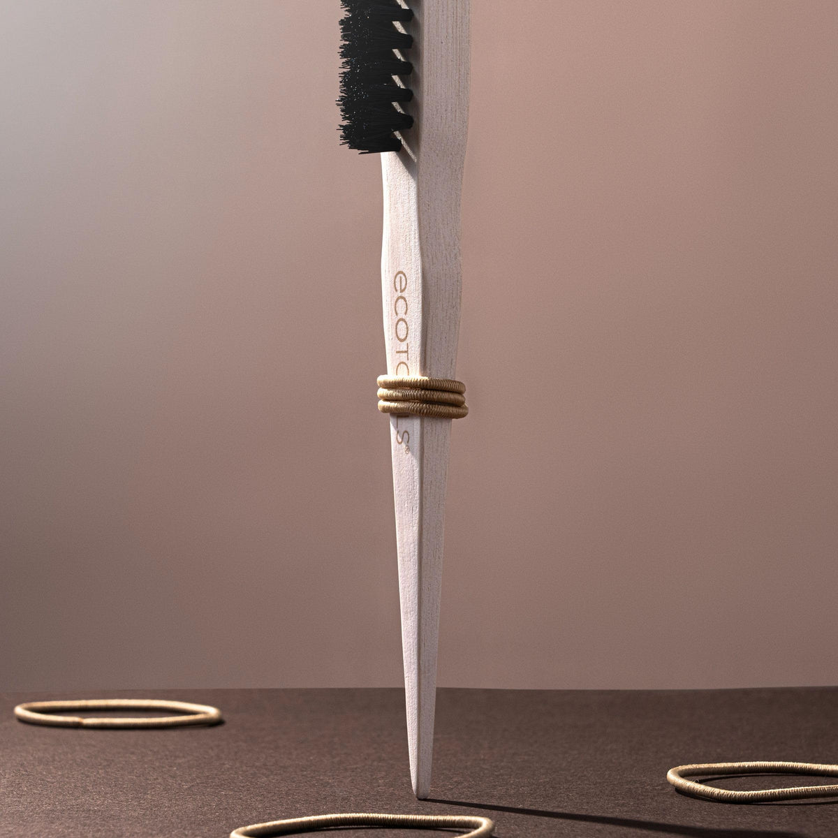 EcoTools brush next to gel and pomade for slick back styling convenience
