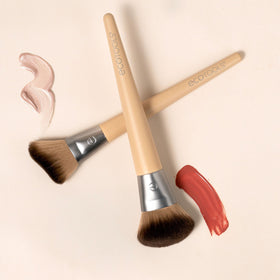 EcoTools highlighter brush applying glow to brow bone demonstrating targeted shimmer