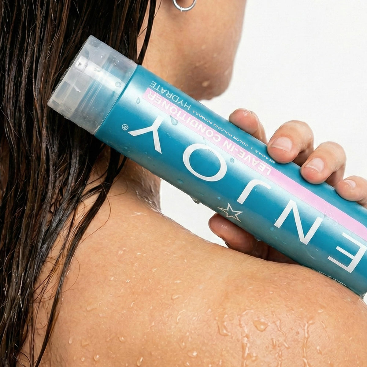 Enjoy leave-in conditioner on bathroom shelf in lifestyle scene promoting daily use