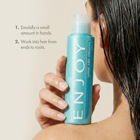 Enjoy 3.4 oz bottle held next to hand to show compact travel-friendly size