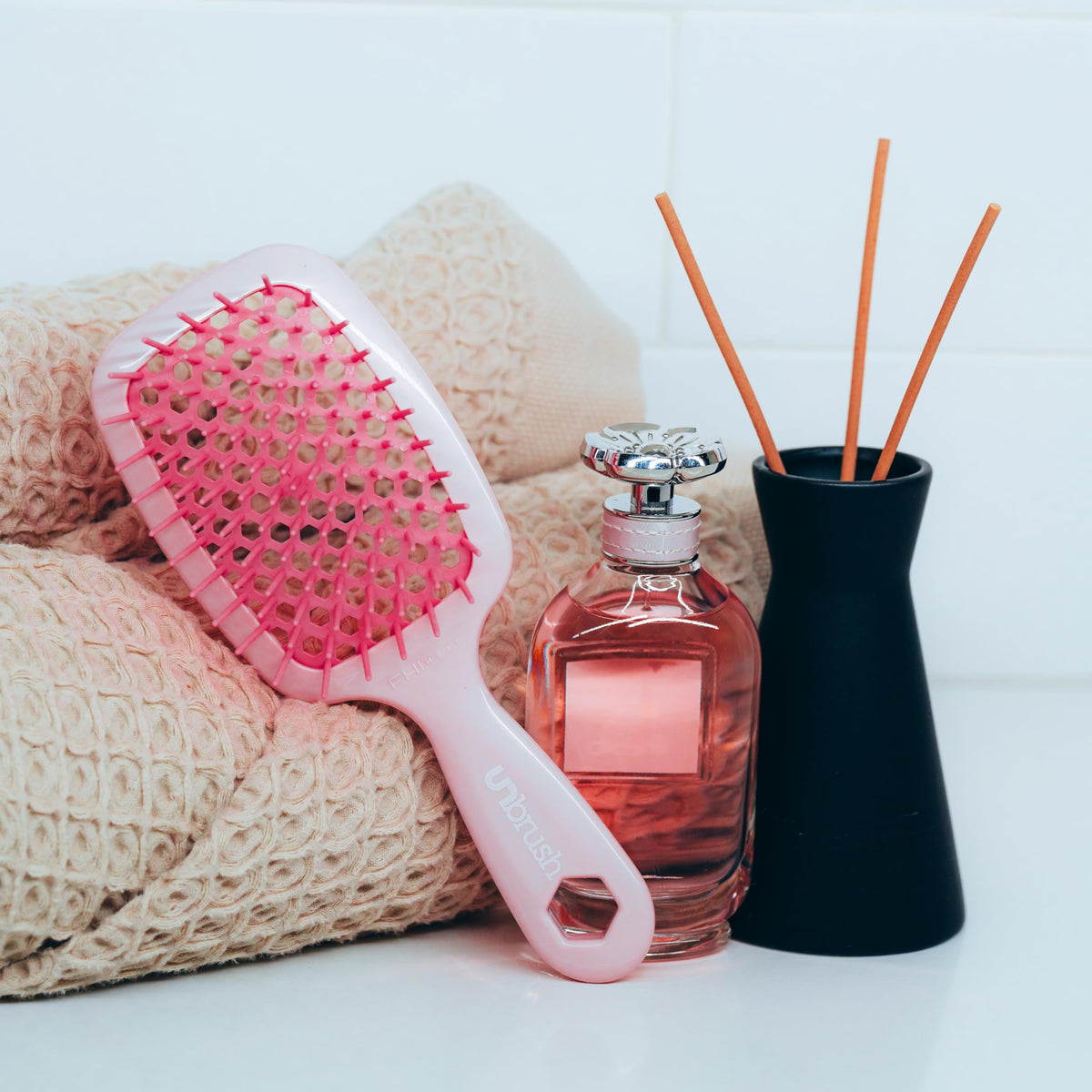 FHI Heat UNbrush on bathroom counter with toiletries portraying everyday and travel-ready use