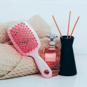 FHI Heat UNbrush on bathroom counter with toiletries portraying everyday and travel-ready use