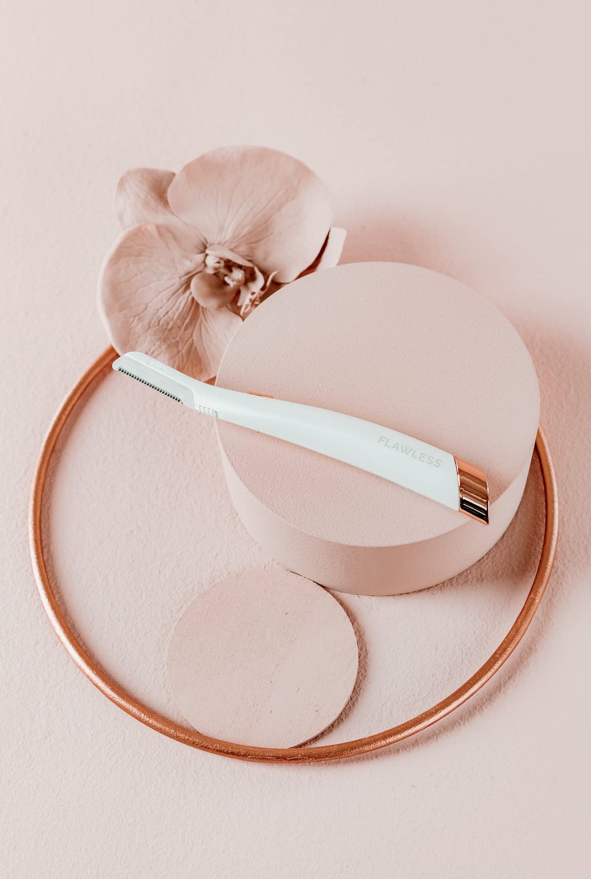 Flawless Dermaplane Glo held in hand to show size and ergonomic grip for controlled use