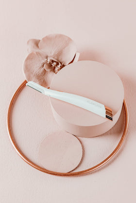 Flawless Dermaplane Glo held in hand to show size and ergonomic grip for controlled use