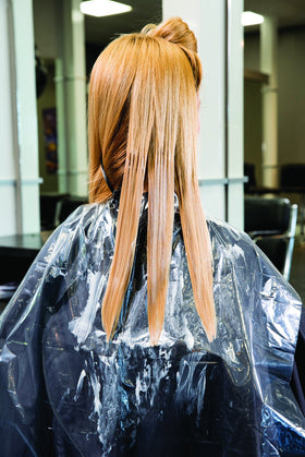 FRAMAR sheet hanging over salon cape in use offering quick cleanup advantage