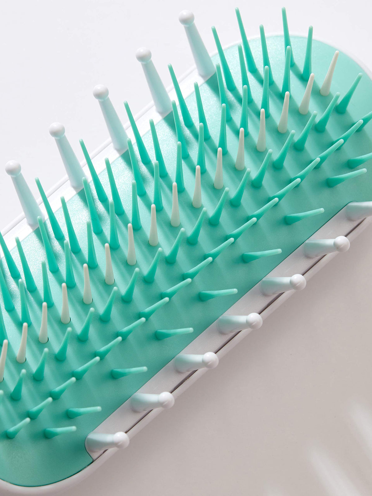 Frida Baby detangler with protective cap inside a packed bag, keeps bristles clean on the go