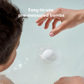 Frida Baby bath bomb beside a coin to show compact size for storage and on-the-go use