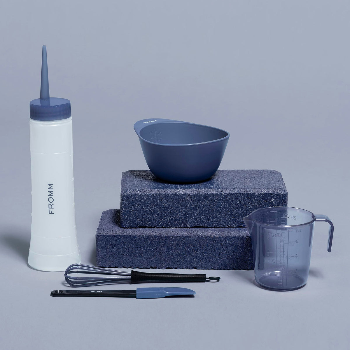 Fromm bottle held in hand for size scale and ergonomic squeeze dispensing advantage