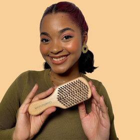 GranNaturals brush held next to hand showing compact size and travel convenience