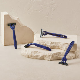 Harry's razor next to a coin showing compact size and portability