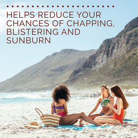 Hawaiian Tropic lip balm pictured on sand with sunglasses emphasizing outdoor use