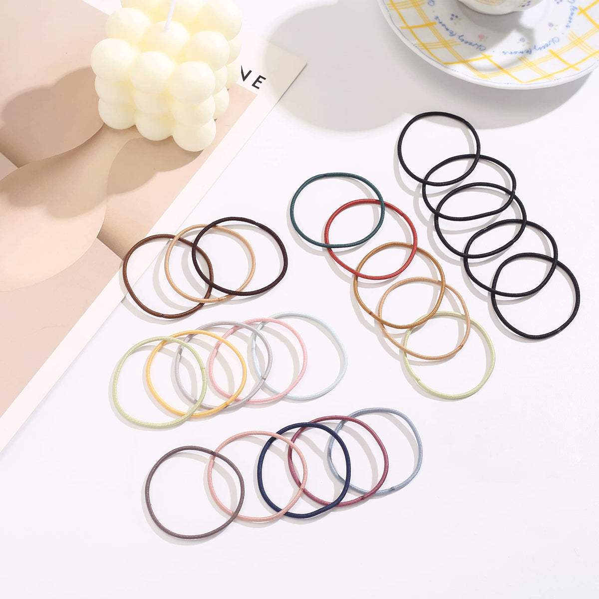 Helamvly single hair tie beside ruler to show 2mm thickness and compact size benefit