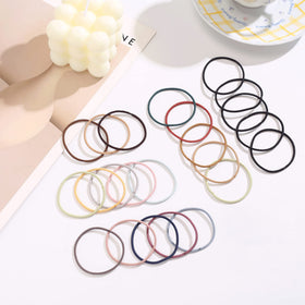 Helamvly single hair tie beside ruler to show 2mm thickness and compact size benefit