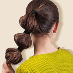 IKOCO hair tie next to coin illustrating compact size and portability