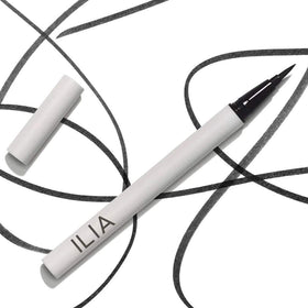 ILIA next to coin for scale showing compact travel-friendly size