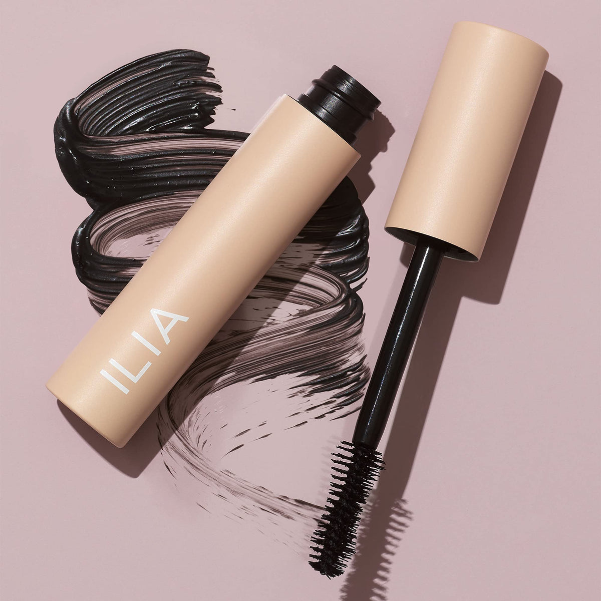 ILIA mascara next to a coin to show compact travel-friendly size
