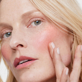 ILIA applying multi-stick to cheek for natural flush and quick touch-up benefit