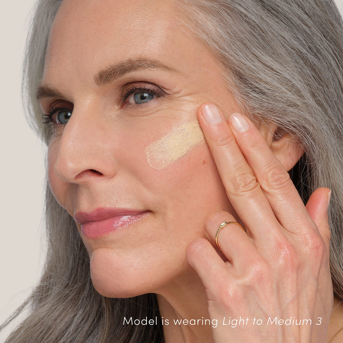 jane iredale model applying HydroPure on face for a dewy natural finish and even tone