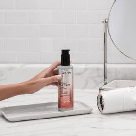Joico Dream Blowout bottle held in hand to show 6.7 fl oz scale and travel-friendly size