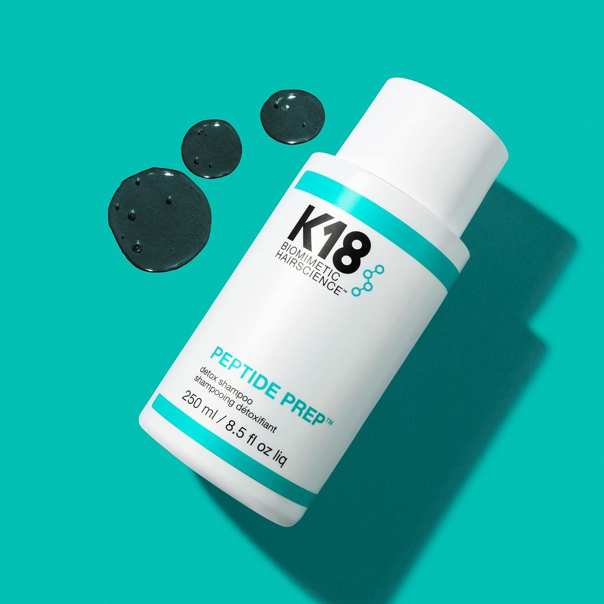 Hand holding K18 bottle to show 16 fl oz scale and portability