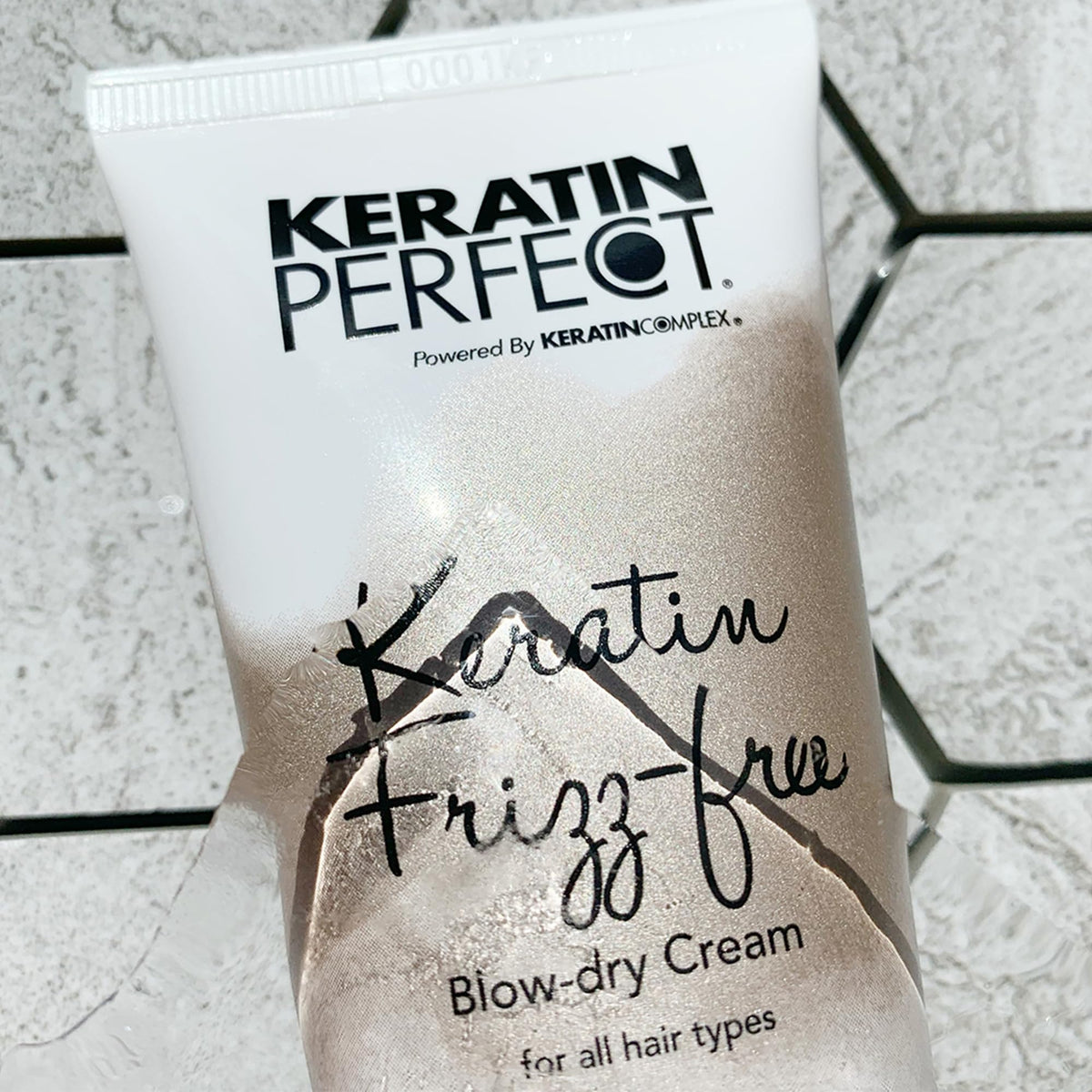 Keratin Perfect tube beside passport showing travel-friendly 2.5oz size for on-the-go convenience