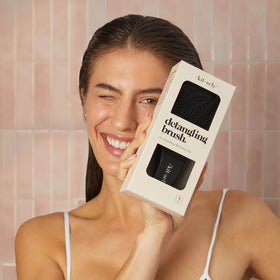 Kitsch brush used by parent on child in bright bathroom for tear-free detangling
