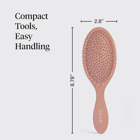 Kitsch brush held in hand to show scale and travel-friendly convenience