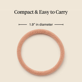 Kitsch hand holding hair tie to show scale and easy-carry convenience benefit