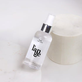 L'ANGE HAIR Rival Heat Shield 4 oz bottle in hand showing compact travel-friendly size
