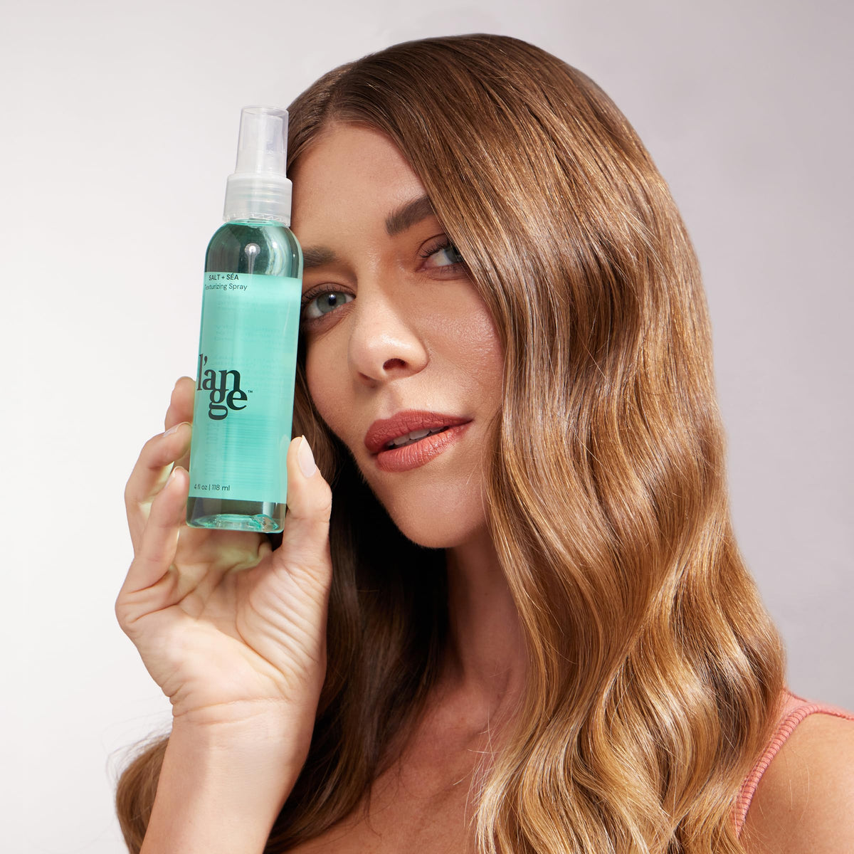 L'ANGE HAIR applying spray to damp hair to create natural waves