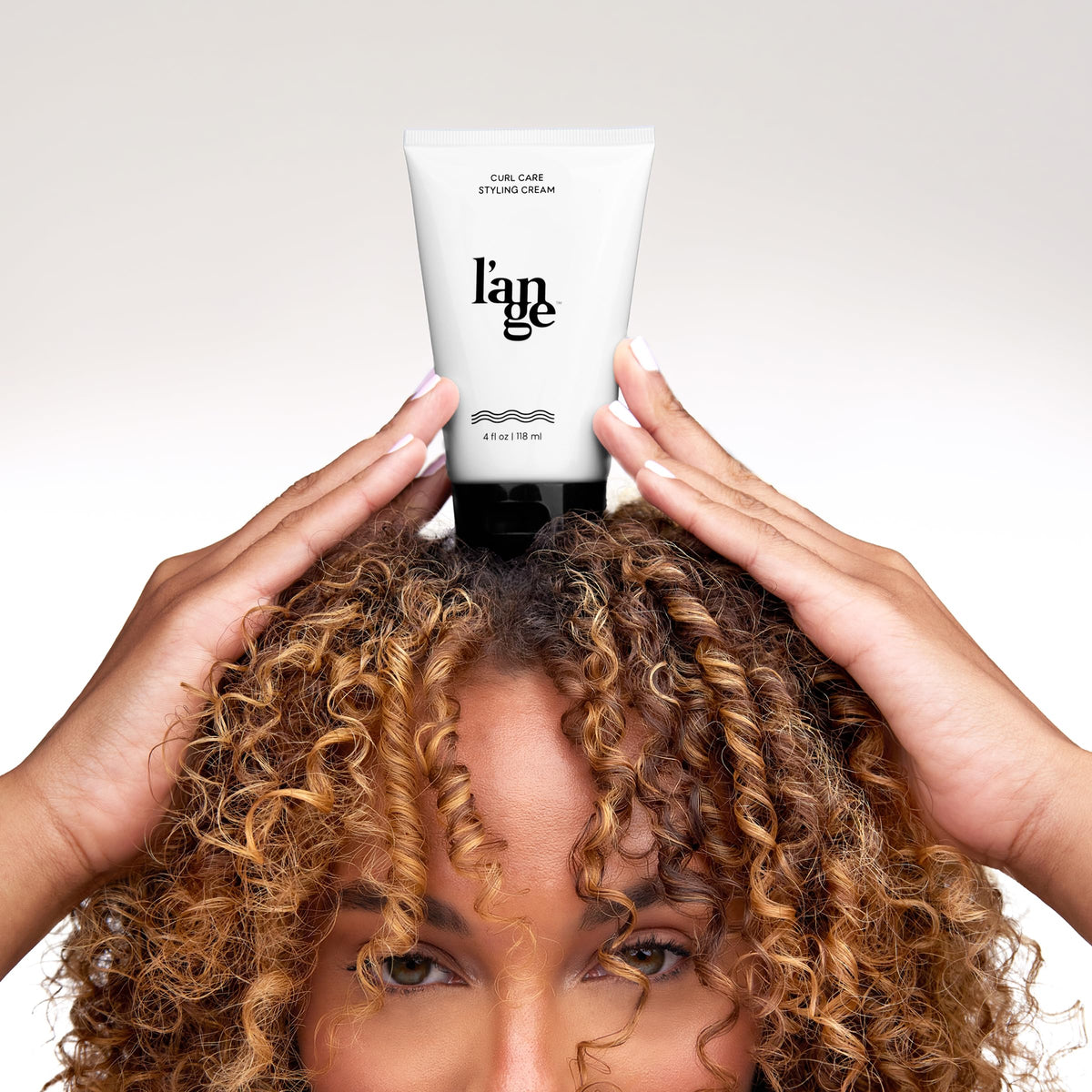 L'ANGE HAIR 8 oz jar beside a hand to show size and portability