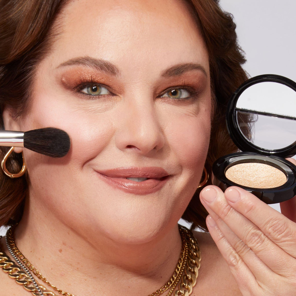 LAURA GELLER NEW YORK compact held in hand to show travel-size scale and portability