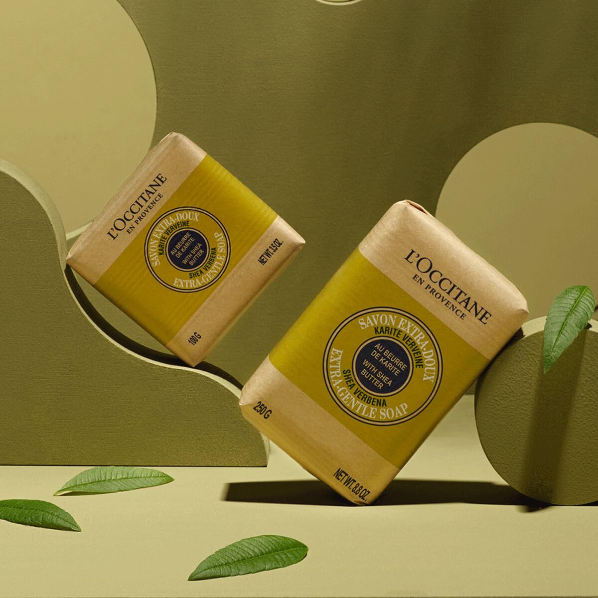 L'Occitane shea verbena soap beside a hand illustrating compact travel-friendly size