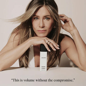 Model using LolaVie spray while blow-drying to create root lift and volume