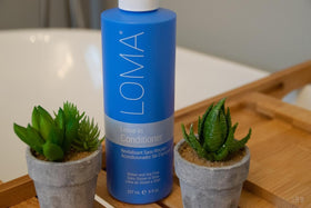 Loma leave-in conditioner mist close-up mid-air over hair — even coverage benefit