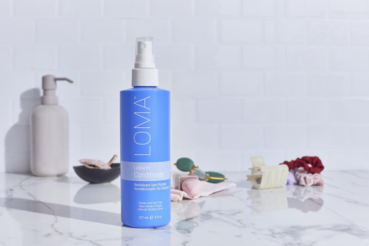 Loma leave-in conditioner on bathroom shelf styled with towels showing daily routine ease