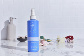 Loma leave-in conditioner on bathroom shelf styled with towels showing daily routine ease