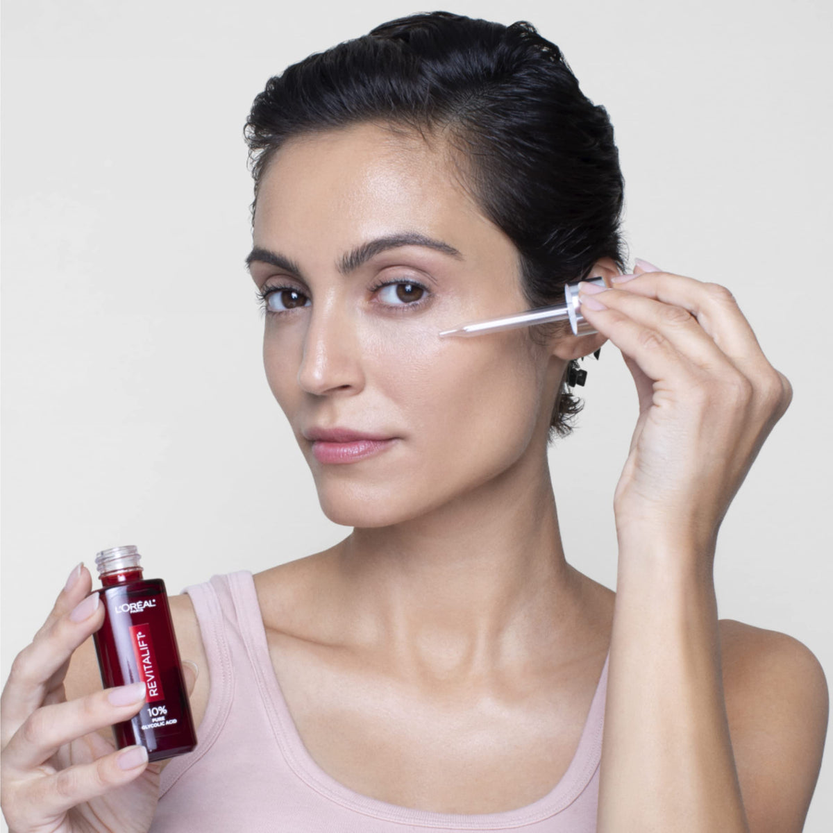 L'Oreal Paris 30ml bottle next to common objects to show compact size for travel