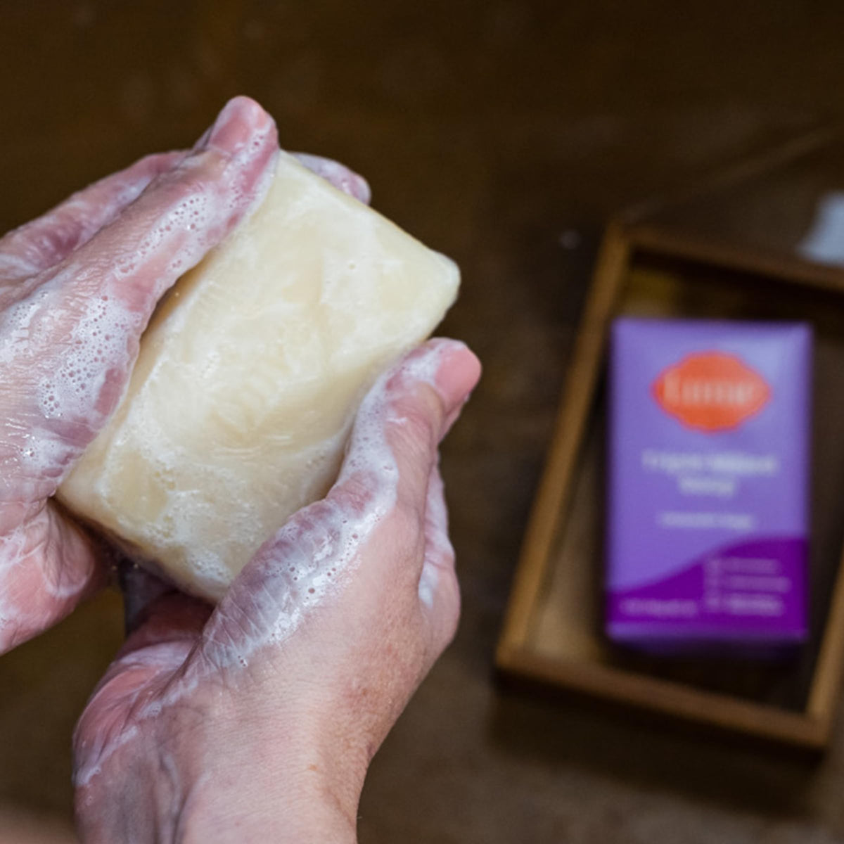 Lathered Lume soap in hand showing rich foam for moisturizing cleanse