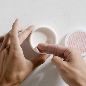 MALIN+GOETZ pomade held in hand to show 2 oz size and travel-friendly benefit