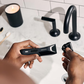 MANSCAPED trimmer next to a hand for scale showing compact, travel-friendly size