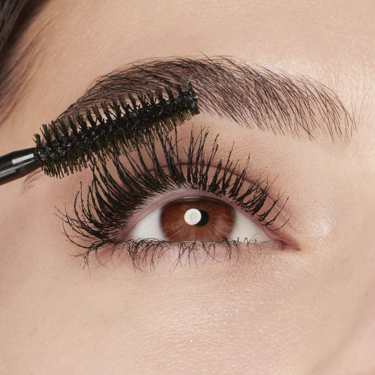 Model applying Maybelline mascara to lashes for dramatic volume